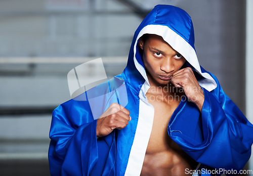 Image of Black man, boxer and champion in robe at gym getting ready for fight, challenge or sports competition. Serious African male person or boxing fighter with fists in preparation for MMA match or game