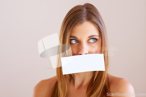 Image of Woman, looking and cover for mouth with mock up for silence in studio on white background. Female model, face and placard for talking, shh or quiet with copy space for announcement, secret or gossip