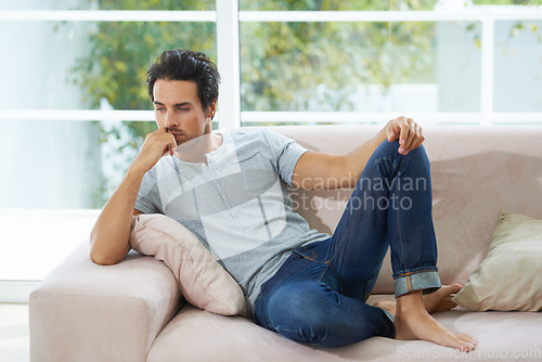 Image of Depression, thinking and man on a sofa with stress, anxiety or broken heart in his home. Sad, crisis or male person in living room overthinking, disaster or lonely, worried or disappointed in a house