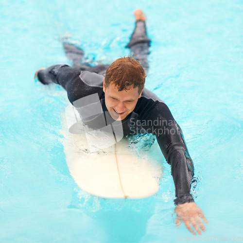 Image of Man, surfing and happy in water, sports and exercise on vacation, holiday and adventure in ocean. Male person, athlete and smile for hobby, paddle and freedom in nature, active and fitness on board