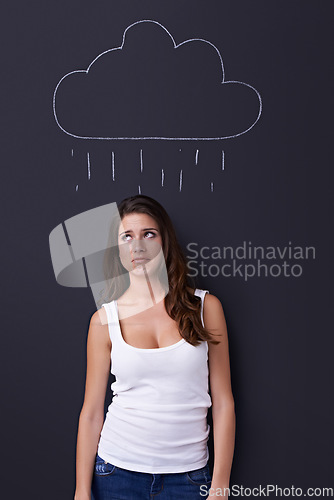 Image of Thinking, sad and rain cloud with woman on a chalkboard for drawing, emotion or expression in studio. Depression, idea or weather and an unhappy young person with a chalk picture of a winter storm