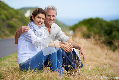 Image of Couple, face and happy outdoor with relax, communication and peace for bonding, relationship or roadtrip. Mature, man and woman with smile, sitting and break in nature with travel, vacation and trust