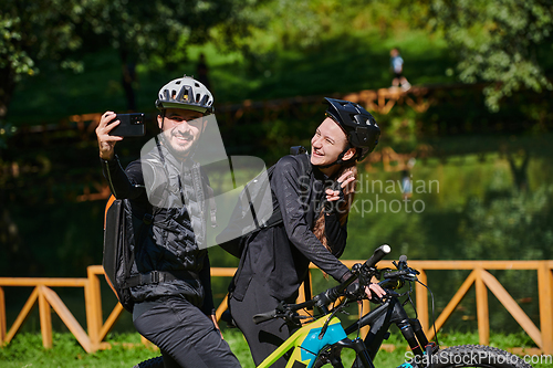 Image of A modern couple captures the joy of their bike ride in the park through a trendy selfie, blending technology and outdoor adventure to immortalize a moment of happiness and togetherness