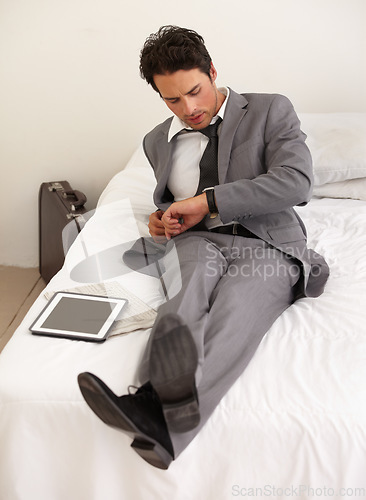 Image of Businessman, watch and checking time on bed at hotel for schedule, reservation or reminder at house. Man or employee looking at wristwatch for monitoring stay, deadline or accommodation in bedroom