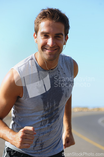 Image of Happy man, portrait and running on road in fitness for exercise, cardio or outdoor training. Active male person smile with earphones for run on street or sidewalk in sweat for health and wellness