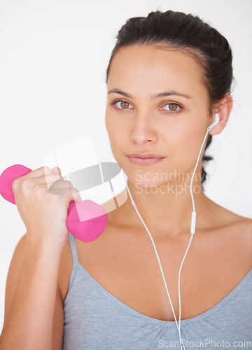 Image of Portrait, fitness with dumbell and a woman with headphones for music while exercising on a white studio background. Strong, arm and health with face of female athlete weightlifting for training