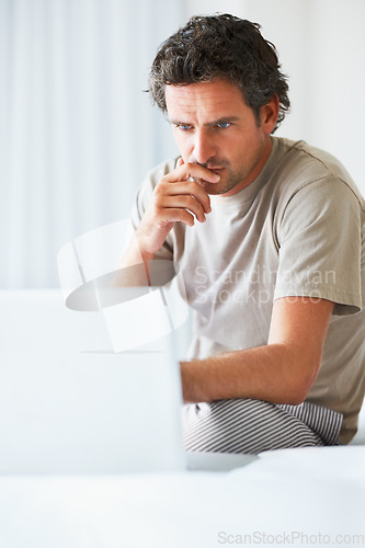 Image of Thinking, man in bedroom and laptop for work from home, serious and sitting in bed for freelance idea. Technology, entrepreneur and remote worker for online job, company and marketing projects