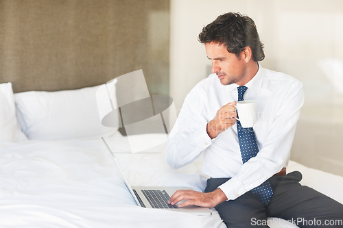 Image of Laptop, bedroom and coffee with a businessman getting ready for work at his home in the morning while checking an email. Corporate, computer on a bed and a professional employee drinking tea