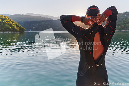 Image of Authentic triathlon athlete getting ready for swimming training on lake