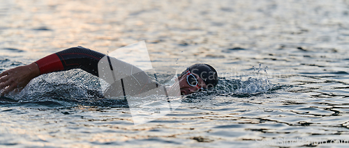 Image of A professional triathlete trains with unwavering dedication for an upcoming competition at a lake, emanating a sense of athleticism and profound commitment to excellence.
