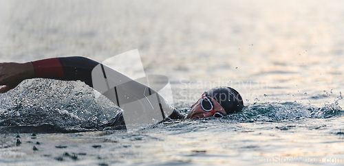 Image of A professional triathlete trains with unwavering dedication for an upcoming competition at a lake, emanating a sense of athleticism and profound commitment to excellence.