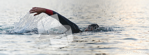 Image of A professional triathlete trains with unwavering dedication for an upcoming competition at a lake, emanating a sense of athleticism and profound commitment to excellence.