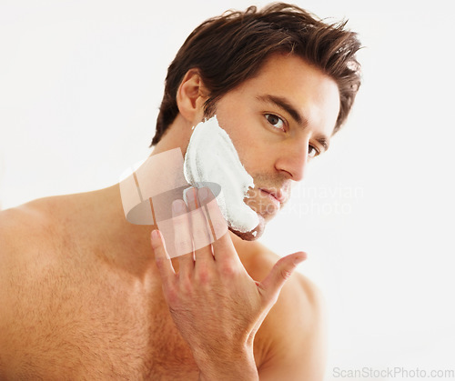 Image of Shaving, cream and face of man in morning, grooming routine and hair removal in bathroom. Cosmetics, beauty and hand with foam, soap or person with self care in home for wellness of skin and body