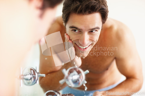 Image of Man, washing face and smile with water for cleaning in bathroom, mirror and reflection for bacteria and facial hygiene. Person, hand and sink for skincare with soap for grooming, health or wellness