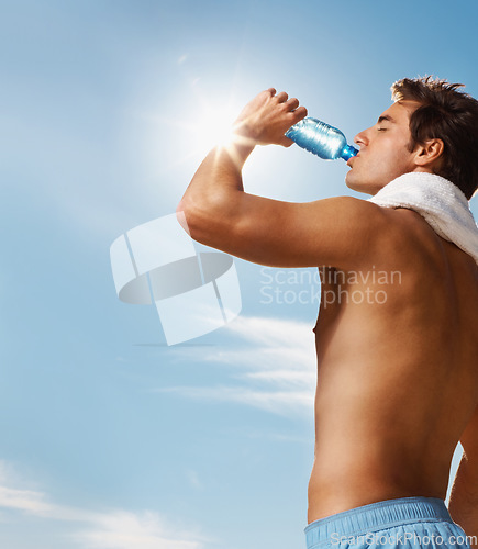 Image of Man, drinking water and bottle with towel for workout, health body and fitness and vacation. Model, thirsty and natural glow with h2o drink for hydration and post cardio exercise by sky background