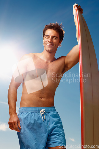 Image of Man, surfing and board with smile by sky, summer or ready for fitness, health or training. Athlete, surfer and sunshine on holiday, happy or thinking outdoor for ideas, workout or exercise in nature