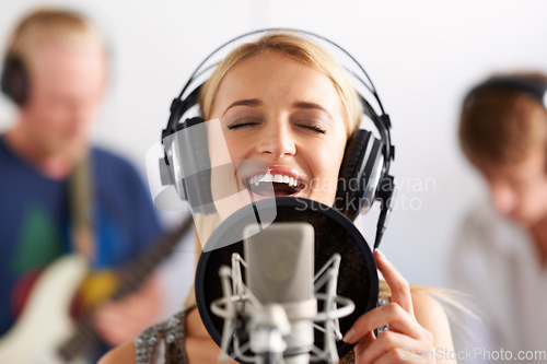 Image of Happy woman, singer and microphone with headphones in music recording studio, sound track or podcast. Female person, blonde or musician smile on mic for audio listening, content creation and karaoke