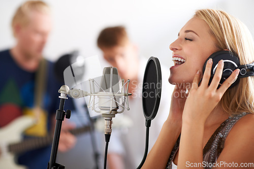 Image of Music, performance and woman with microphone, headphones and singing band with talent. Recording studio, art and happy girl musician live streaming song for record label, sound and audio broadcast.