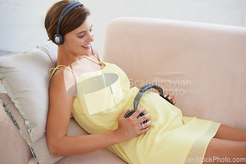 Image of Woman, music or headphones on pregnant stomach in home living room for sound, audio or listening development for baby. Relax, pregnancy or person with podcast for childcare wellness or growth support