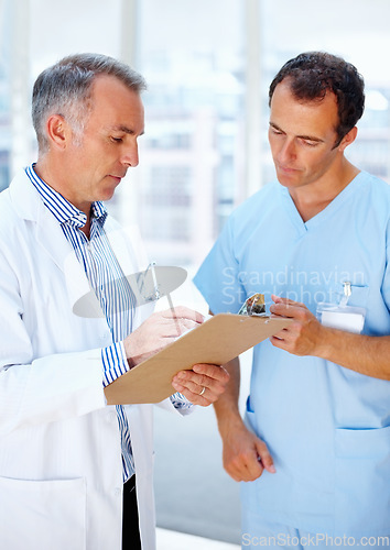 Image of Healthcare, doctor and nurse with a clipboard, conversation and communication with test results, sign and wellness. Staff, medical and professional with documents, career and talking with physician