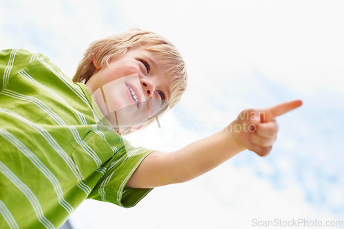 Image of Boy, happy child and pointing at blue sky outdoor in low angle, summer mockup and show direction. Young cute kid, finger and hand gesture at clouds, playing and freedom for education below with smile