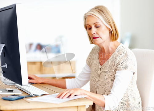 Image of Mature woman at desk with computer, documents and administration for business accounting. Report, review and senior businesswoman reading invoice paperwork for finance, budget and office management.