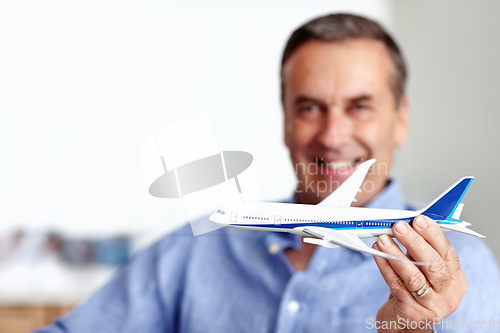 Image of Mature man, flight and toy plane for travel, vacation and holiday planning with a smile at home. Happy, airplane model and retirement of a male person with confidence from trip and air traveling