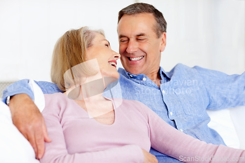 Image of Senior, couple and face or laughing on sofa with support, relationship and bonding in retirement home. Elderly, man and woman with smile on couch in living room with relax, care and love in house