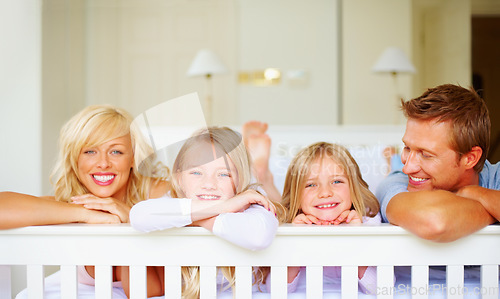 Image of Portrait, happy and a family lying on a bed together while in their home on a weekend morning. Face, love and the smile of a mom, dad and children in the bedroom of an apartment to relax for bonding