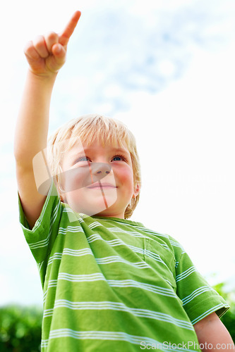 Image of Boy, child and pointing at space outdoor in low angle, summer mockup and show direction. Young cute kid, finger and hand gesture at blue sky clouds, park and nature garden, playing and freedom