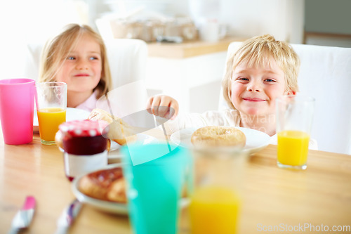 Image of Smile, kitchen and children eating breakfast together for healthy, wellness and diet meal. Happy, laughing and kid siblings bonding and enjoying lunch or brunch with juice at table in family home.