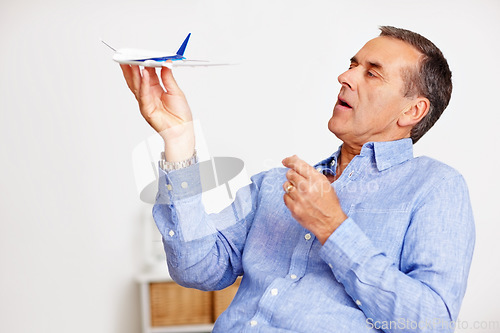 Image of Mature man, flying and toy plane for travel, vacation and holiday planning with a smile at home. Happy, airplane model and retirement of a male person with confidence from trip and air traveling