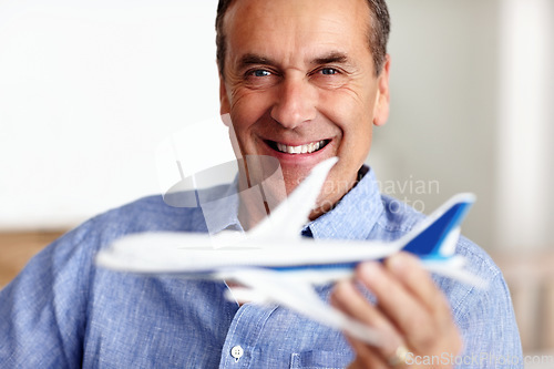 Image of Mature man, portrait and toy plane for travel, vacation and holiday planning with a smile at home. Happy, airplane model and retirement of a male person with confidence from trip and air traveling