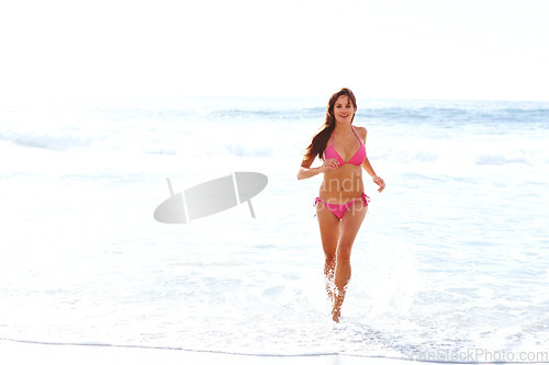 Image of Waves, running and happy woman in bikini on beach for summer vacation, travel and tropical island. Relax, playing and girl with smile at ocean for holiday with water, sunshine and energy in Hawaii.