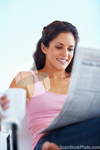 Image of Happy woman, reading and newspaper with coffee and morning headlines for wellness in living room. Young person, smile and espresso to relax on weekend and current events with warm drink in apartment