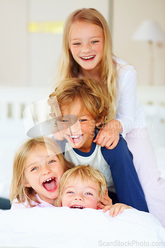 Image of Portrait, laughing or crazy with brother and sister sibling children on a bed in their home together. Family, funny or silly with young boy and girl kids in the bedroom of an apartment on the weekend
