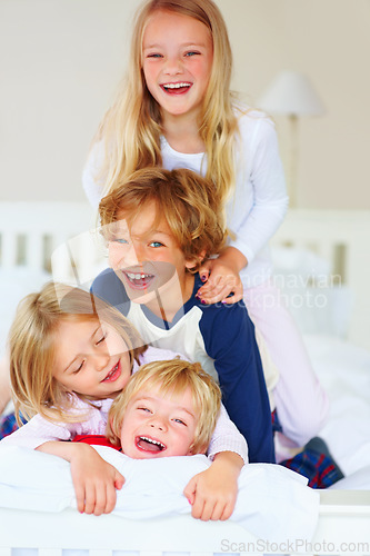 Image of Portrait, funny or playful with brother and sister sibling kids on a bed in the home together. Family, love or laughing with young boy and girl children in the bedroom of an apartment on the weekend