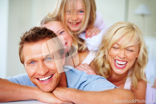 Image of Portrait, love and a family laughing on a bed together while in the home on a weekend morning. Face, smile and a funny father, mother and children in the bedroom of an apartment to relax for bonding