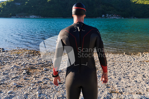 Image of Authentic triathlon athlete getting ready for swimming training on lake