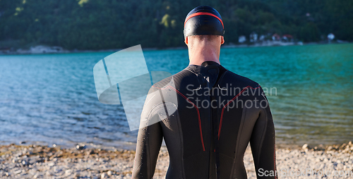 Image of Authentic triathlon athlete getting ready for swimming training on lake