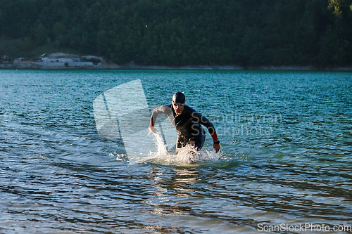 Image of Triathlon athlete starting swimming training on lake