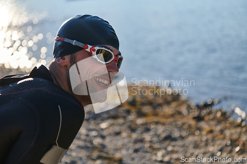 Image of Authentic triathlon athlete getting ready for swimming training on lake