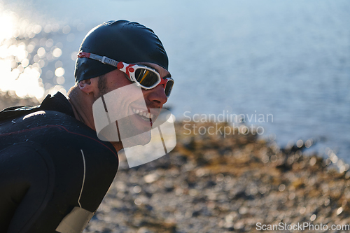 Image of Authentic triathlon athlete getting ready for swimming training on lake