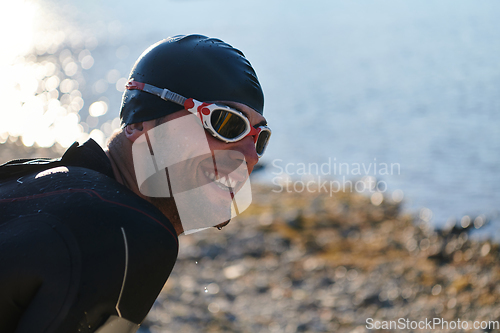 Image of Authentic triathlon athlete getting ready for swimming training on lake