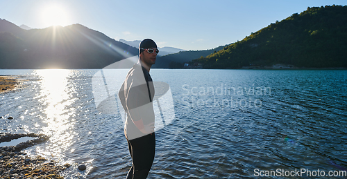 Image of Authentic triathlon athlete getting ready for swimming training on lake