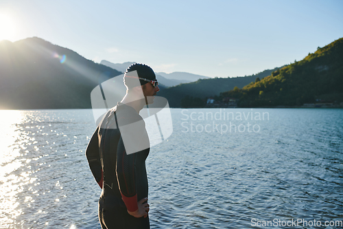 Image of Authentic triathlon athlete getting ready for swimming training on lake