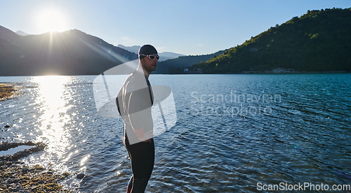 Image of Authentic triathlon athlete getting ready for swimming training on lake