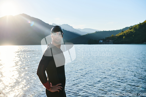 Image of Authentic triathlon athlete getting ready for swimming training on lake