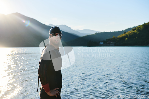 Image of Authentic triathlon athlete getting ready for swimming training on lake