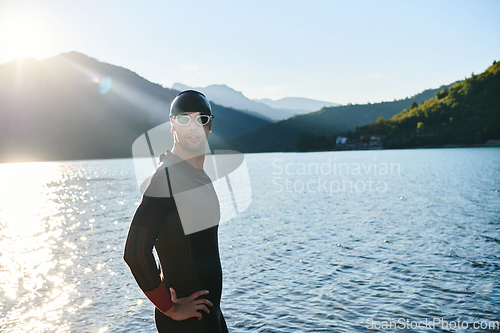 Image of Authentic triathlon athlete getting ready for swimming training on lake